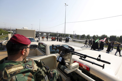 An Iraqi security forces guards as Shi'ite pilgrims walk to the holy city of Kerbala, ahead of the holy Shi'ite ritual of Arbaeen, in Baghdad, 