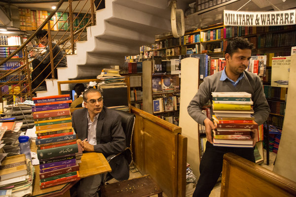 Ahmad Saeed, left, overseeing the cataloging of new arrivals before they are put on the store's shelves. He inherited this business from his father, the founder, Saeed Jan Qureshi. Credit: Danial Shah for The New York Times
