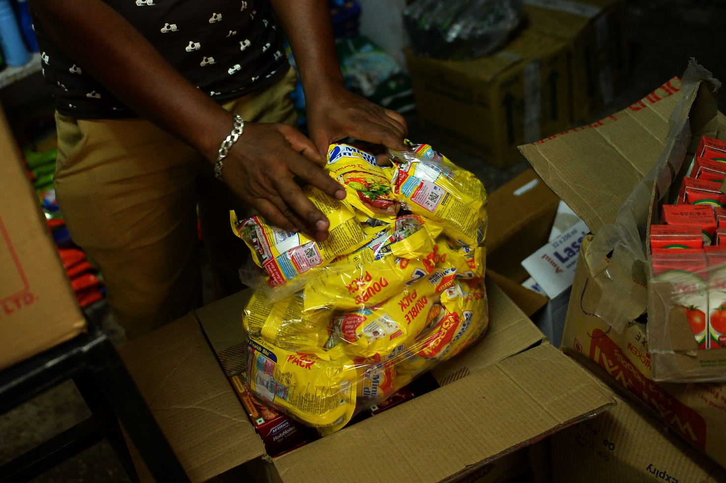 In this photograph taken on June 17, 2015, an Indian shopkeeper puts packs of Nestle 'Maggi' instant noodles into a plastic bag in his shop in New Delhi.  Nestle chief Paul Bulcke said that he wanted to see its hugely popular Maggi brand of instant noodles back on the Indian market as soon as possible after it was banned over a health scare. India's food safety regulator on June 5 banned the product after tests that it said showed the noodles contained excessive levels of lead.  AFP PHOTO/Chandan KHANNA
