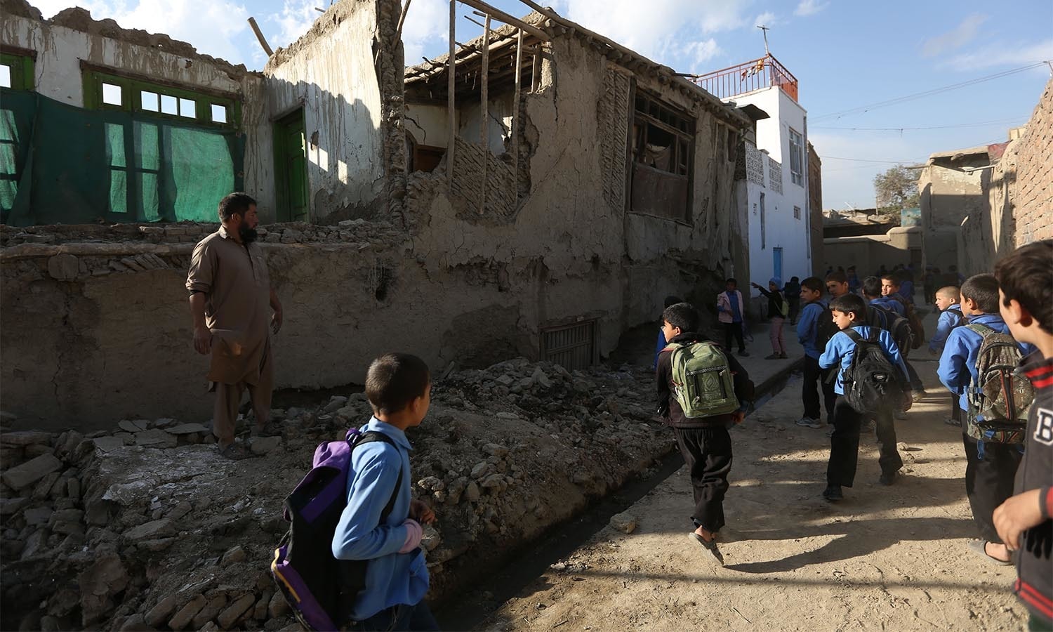 Afghan school boys walk to look a damaged house following a powerful earthquake that could be felt across South Asia, in Kabul, Afghanistan, Monday, Oct. 26, 2015. In Afghanistan's Takhar province, west of Badakhshan, at least 12 students at a girls' school were killed in a stampede as they tried to get out of the shaking buildings, a local official says. Sonatullah Taimor, the spokesman for the Takhar provincial governor, says another 30 girls have been taken to the hospital in the provincial capital of Taluqan. (AP Photo/Rahmat Gul)