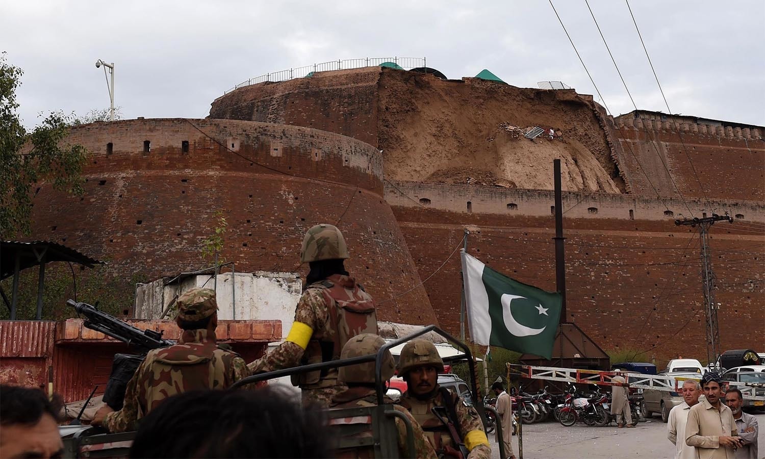 Pakistani paramilitary soldiers observe the damaged wall of a fort used by security forces after an earthquake in Peshawar on October 26, 2015. At least 17 people including eight children were killed in Pakistan when a 7.5 magnitude quake struck in Afghanistan October 26, officials said. AFP PHOTO / A MAJEED