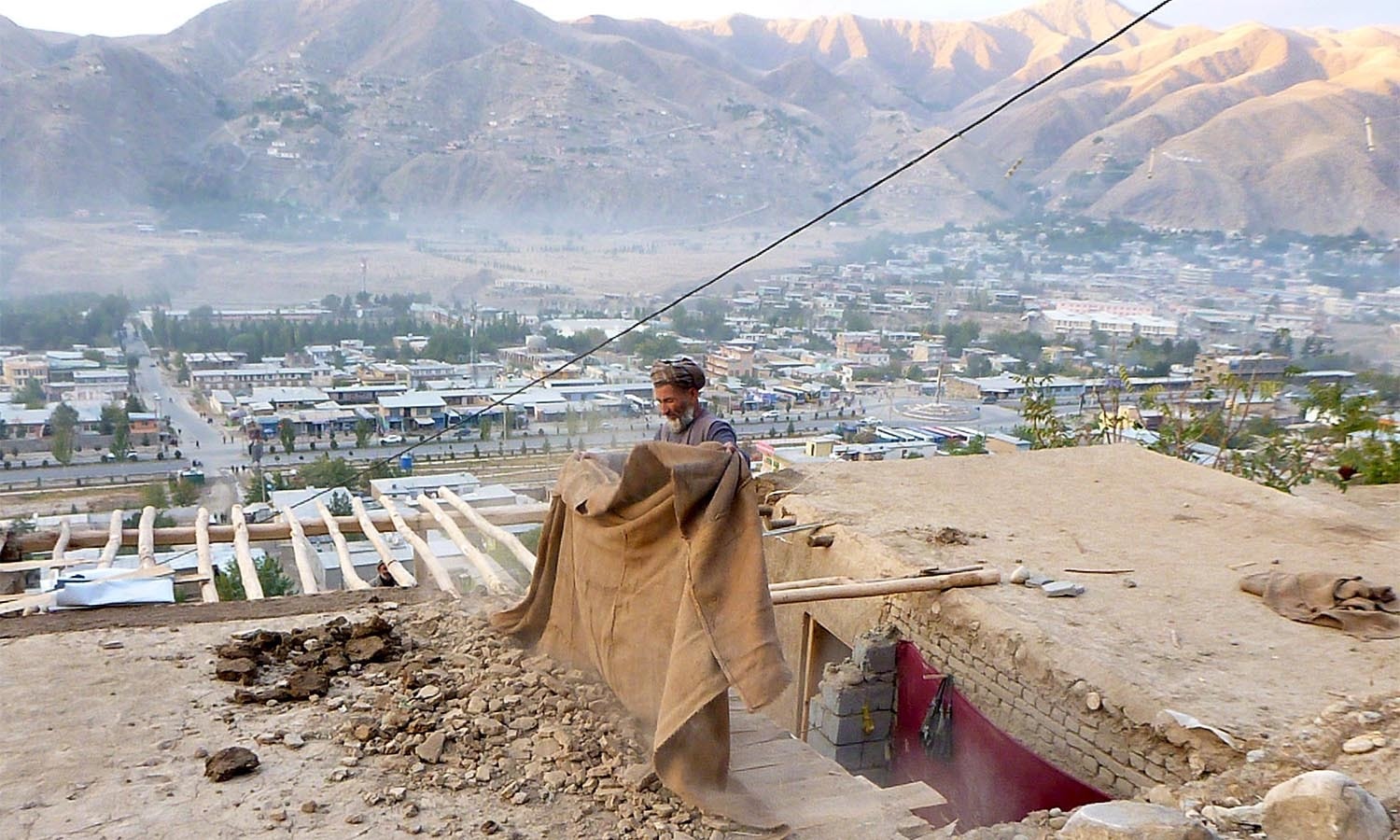 A man clears rubbles from the roof of his house after an earthquake, in Fayzabad capital of Badakhshan province, Afghanistan October 26, 2015. A powerful earthquake struck a remote area of northeastern Afghanistan on Monday, shaking the capital Kabul, as shockwaves were felt in northern India and in Pakistan's capital, where hundreds of people ran out of buildings as the ground rolled beneath them. REUTERS/Stringer          EDITORIAL USE ONLY. NO RESALES. NO ARCHIVE