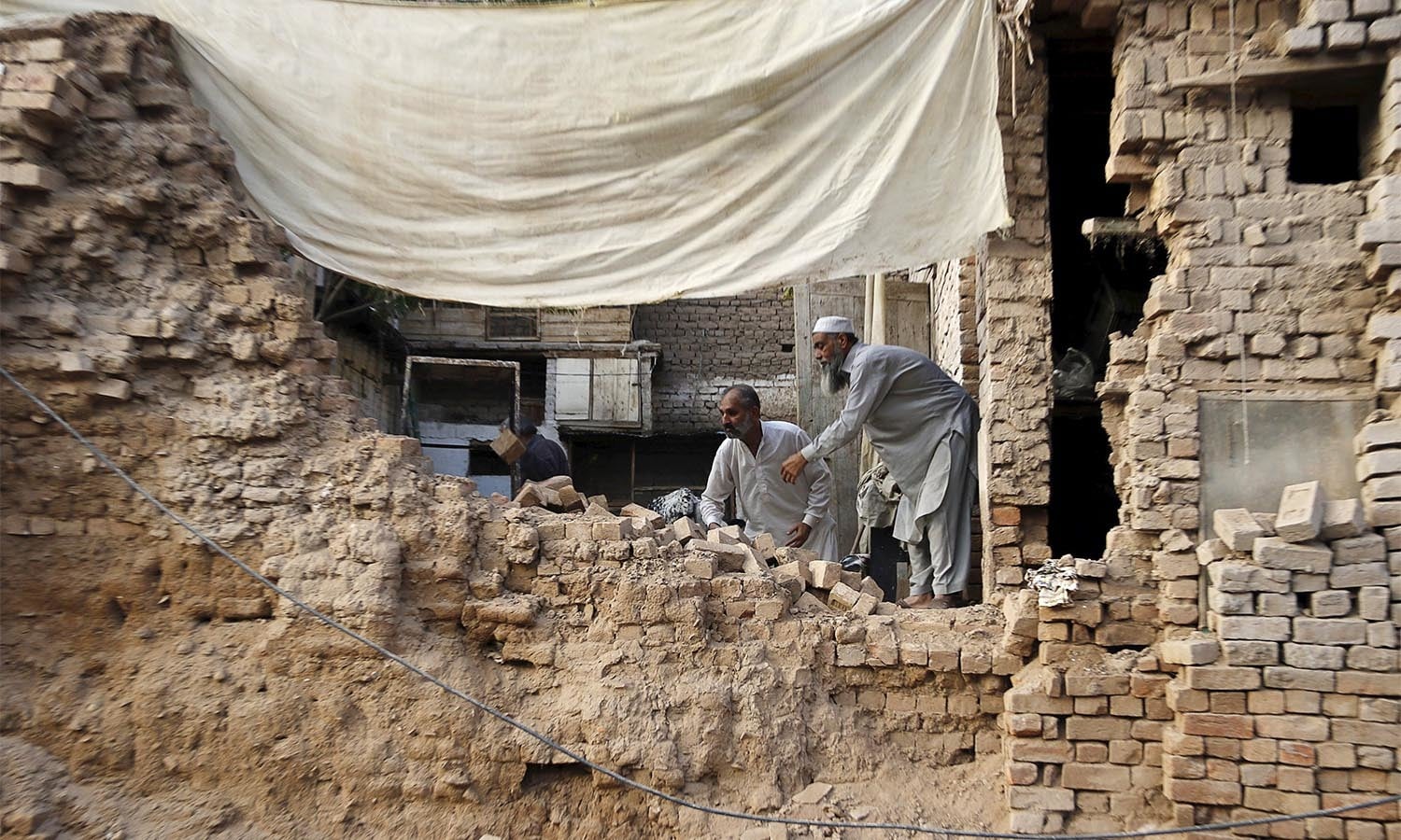 Residents clear the rubble of a house after it was damaged by an earthquake in Peshawar, Pakistan October 26, 2015. A powerful earthquake struck a remote area of northeastern Afghanistan on Monday, shaking the capital Kabul, as shockwaves were felt in northern India and in Pakistan's capital, where hundreds of people ran out of buildings as the ground rolled beneath them. REUTERS/Khuram Parvez