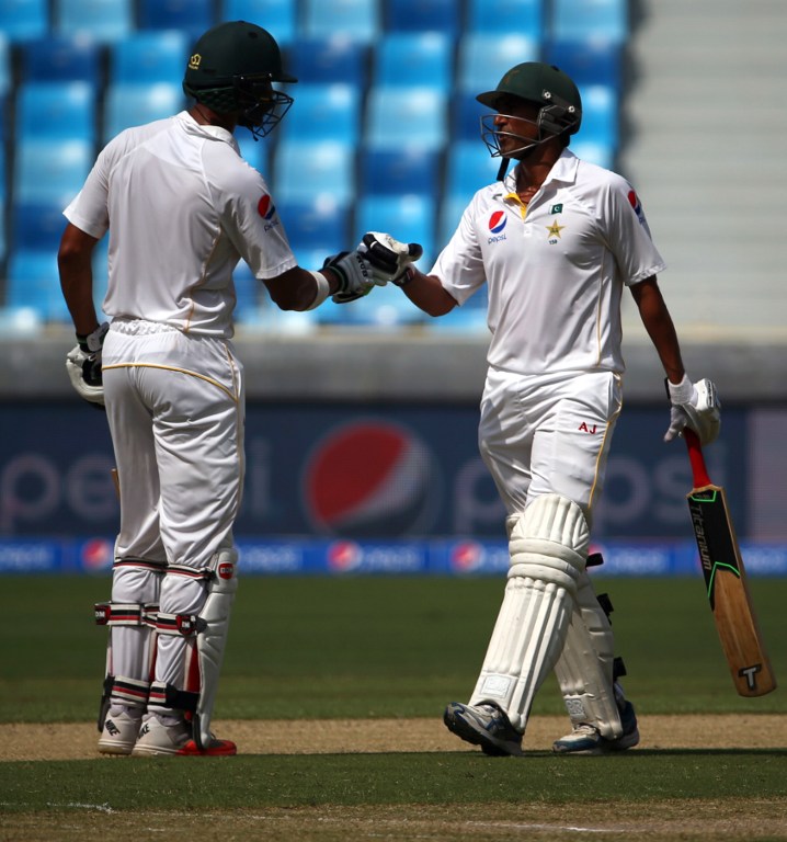 Pakistan's Younis Khan (R) greets his teammate Shan Masood during the first day of the second Test cricket match between Pakistan and England in Dubai on October 22, 2015.       AFP PHOTO/MARWAN NAAMANI