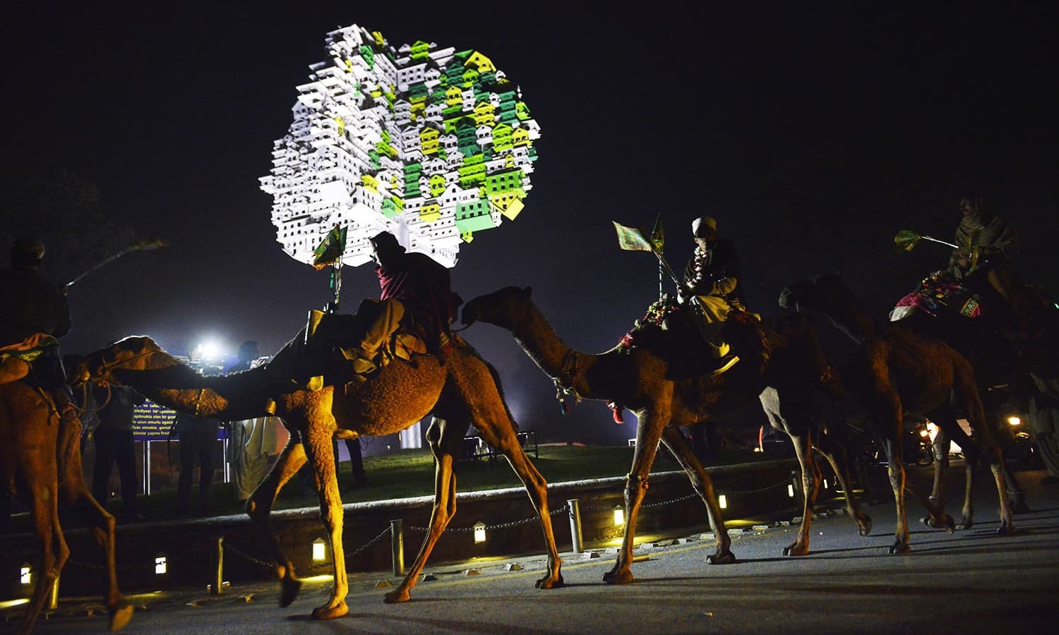Pakistani Muslims ride on a camel during a rally to celebrate the birthday of Prophet Mohammed in Lahore on December 23, 2015. The birthday of Prophet Mohammed, also known as 'Milad', is celebrated during the Islamic month of Rabi al-Awwal, which falls on December 24, 2015 in Pakistan. AFP PHOTO / Arif ALI