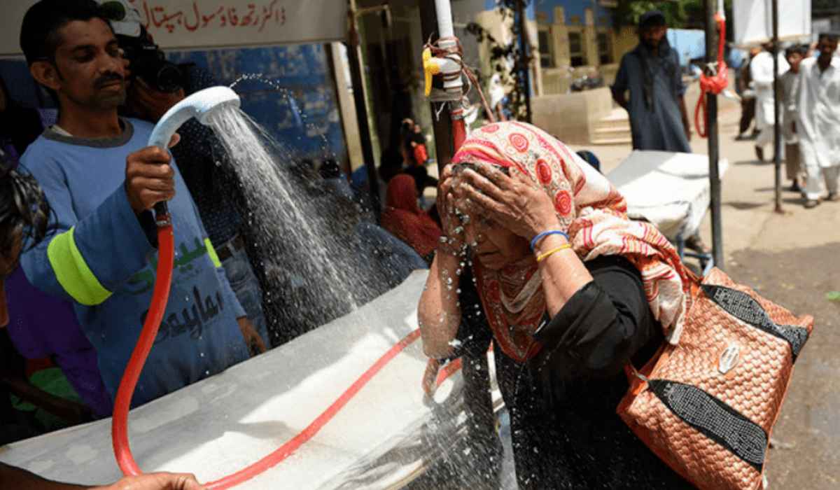 A volunteer showers a woman with water during a heatwave in Karachi
