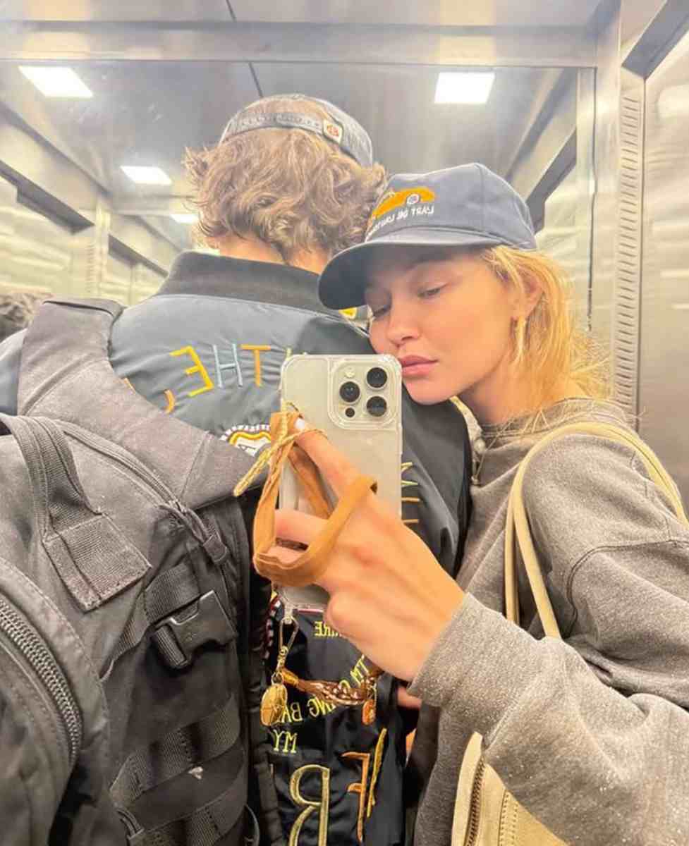 Gigi Hadid takes a selfie with a man who appears to be Bradley Cooper from behind
