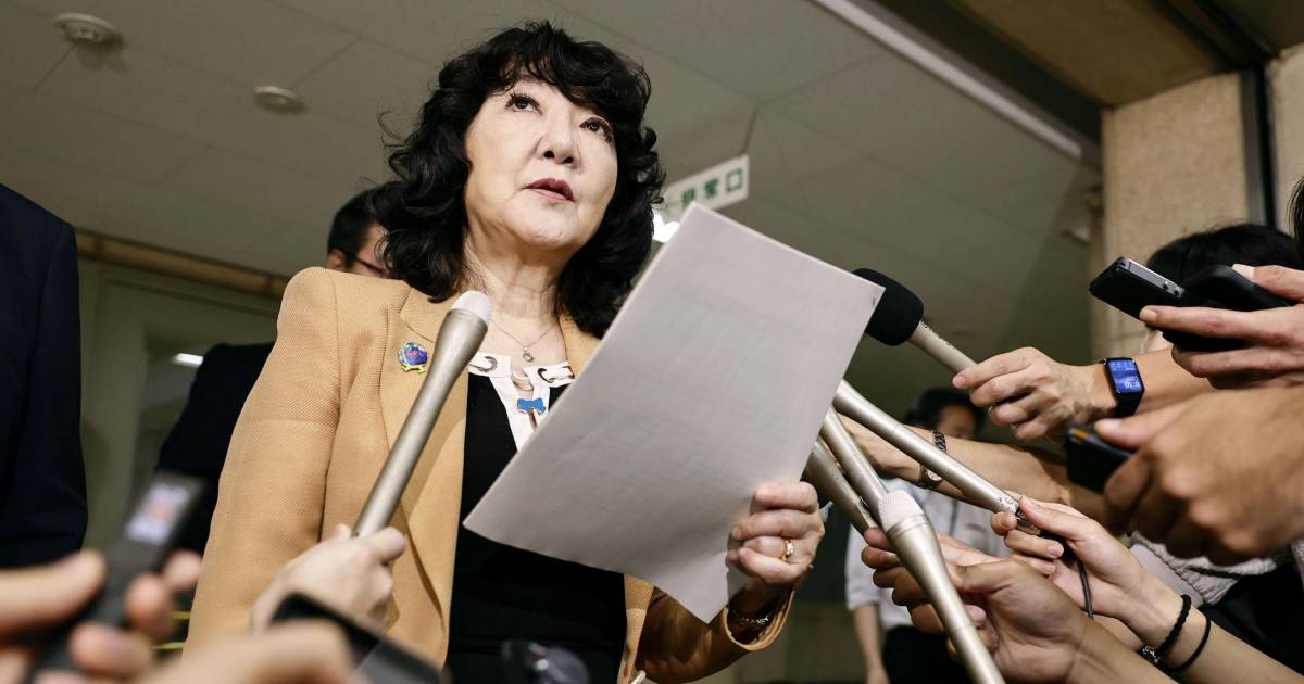 Japanese Finance Minister Satsuki Katayama, wearing a beige jacket and holding a paper document, addresses media microphones during a news conference in Tokyo.